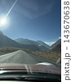 Mountain road viewed through vehicle windshield under bright sun and clear blue sky in rugged valley Mountain road viewed through vehicle windshield under bright sun and clear blue sky in rugged valley 143670638