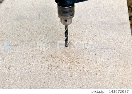 The process of drilling a hole in a wooden board. The process of drilling a hole in a wooden board. 143672087