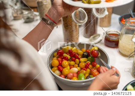 Woman serves colorful cherry tomatoes onto her plate at a hotel breakfast buffet. Healthy food choices and fresh vegetables promote balanced nutrition while traveling Woman serves colorful cherry tomatoes onto her plate at a hotel breakfast buffet. Healthy food choices and fresh vegetables promote balanced nutrition while traveling 143672125