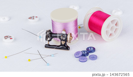 still life of a skein of thread for sewing, needles, buttons, sewing machine on a white background 143672565