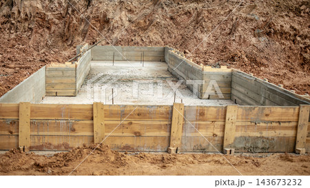 Workers are preparing concrete foundations and pile caps at a construction site. The area has wooden forms set for concrete pouring 143673232