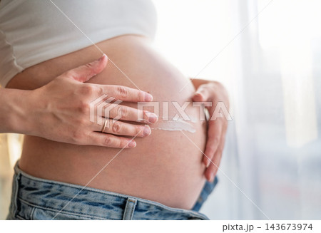 Pregnant Woman Applying Stretch Mark Cream on Her Belly, Skin Care During Pregnancy Concept Pregnant Woman Applying Stretch Mark Cream on Her Belly, Skin Care During Pregnancy Concept 143673974