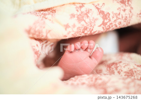 A newborn baby foot rests between cream and pink blankets, with tiny toes sharply focused. The scene connects early parenthood, family love, newborn safety, quiet care, and tender home routines. A newborn baby foot rests between cream and pink blankets, with tiny toes sharply focused. The scene connects early parenthood, family love, newborn safety, quiet care, and tender home routines. 143675268