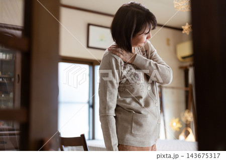 自宅で肩凝りに苦しむミドル・シニア女性 自宅で肩凝りに苦しむミドル・シニア女性 143675317