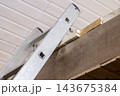 Aluminum ladder leaned against a wooden beam 143675384