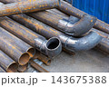 Stacked steel pipes and welded elbow fittings showing rust, weld marks 143675388