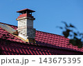 Close-up of a red metal roof and brick chimney 143675395