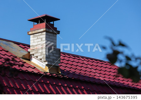 Close-up of a red metal roof and brick chimney Close-up of a red metal roof and brick chimney 143675395