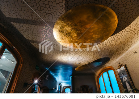 Gold leaf disc lamp on a honeycomb patterned ceiling in a Casa Batllo room 143676081