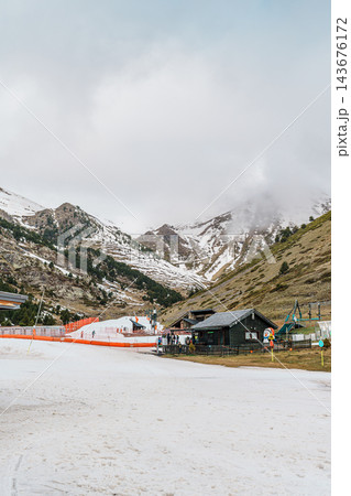 Snow covered play area and wooden chalet at ski resort in Vall de Nuria with misty mountains behind 143676172