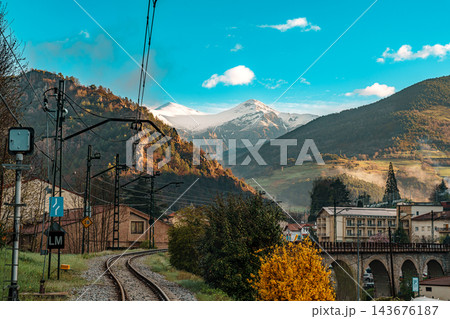 Railway track curving toward snowy Pyrenees peak above Ribes de Fresser village 143676187