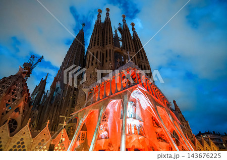 Passion facade of Sagrada Familia lit at dusk under a deep blue cloudy sky 143676225