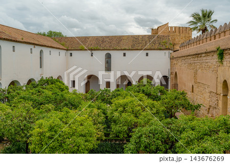 Whitewashed arcaded courtyard with orange trees and crenellated fortress wall at the Alcazar of Cordoba Whitewashed arcaded courtyard with orange trees and crenellated fortress wall at the Alcazar of Cordoba 143676269