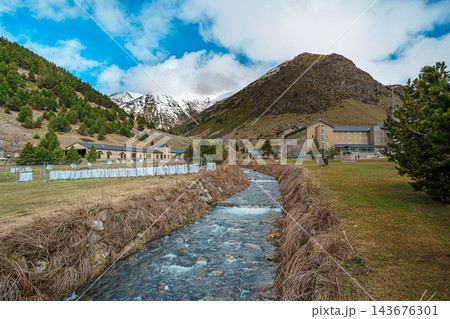 Wooden footbridge over a mountain stream with snowy peaks in Vall de Nuria Wooden footbridge over a mountain stream with snowy peaks in Vall de Nuria 143676301