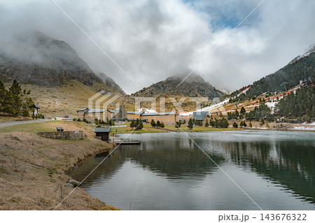 Lakeside gravel path leading to sanctuary below misty mountains in Vall de Nuria 143676322