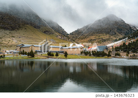 Sanctuary reflected in a calm mountain lake with fog covered peaks in Vall de Nuria 143676323