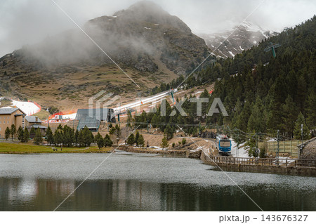 Sanctuary and mountain lake with a blue train and fog covered peaks in Vall de Nuria 143676327