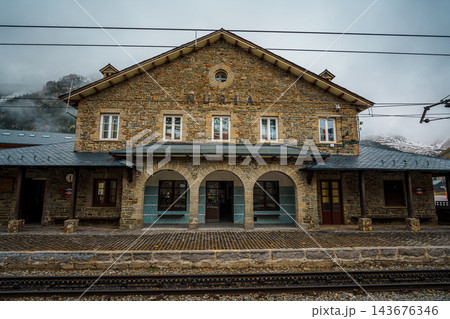 Stone railway station building with arches and name sign beside rack railway tracks in Vall de Nuria 143676346