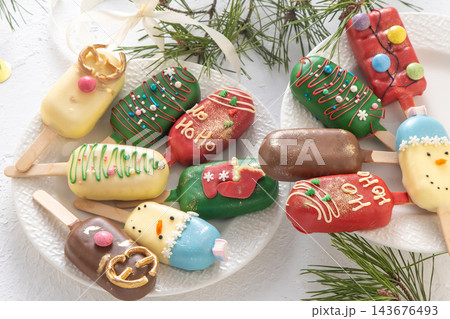 Christmas dessert. Sweet food. Cheesecake on a stick in the shape of ice cream. Children's treat in winter. Candy Christmas tree, snowman, deer and Santa Claus. Gingerbread cookies 143676493