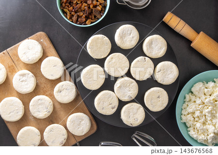 Cheesecakes made from cottage cheese and raisins. Prepare food for breakfast. Syrnik pancakes. Round cheese cake on black background. Cheesecakes made from cottage cheese and raisins. Prepare food for breakfast. Syrnik pancakes. Round cheese cake on black background. 143676568