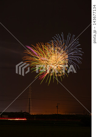 夜空にカラフルに広がる大輪の打ち上げ花火と光跡が走る田んぼのあぜ道からの森町の納涼花火大会風景 143677134