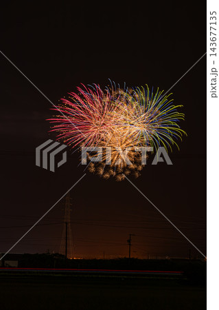 夜空に鮮やかに重なり合う大輪のマルチカラー花火と光跡が走る田んぼのあぜ道からの森町の納涼花火大会風景 143677135