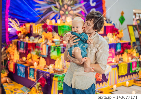 Father giving his baby a kiss beside a festive remembrance altar. Father giving his baby a kiss beside a festive remembrance altar. 143677171