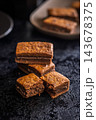 Close-Up Stack Of Chewy Chocolate Brownies With Crumbly Texture On Dark Surface 143678375
