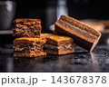 Close-Up Stack Of Chewy Chocolate Brownies With Crumbly Texture On Dark Surface 143678378