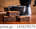 Stacked Chocolate Brownies With Coffee Mug In Cozy Cafe Setting, Close-Up Dessert Photo 143678379