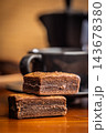 Stacked Chocolate Brownies With Coffee Mug In Cozy Cafe Setting, Close-Up Dessert Photo 143678380