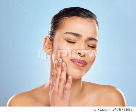 Toothache, pain and woman in studio with dental problem for cavity crisis and decay from bacteria. Female person, hand on face and jaw injury with surgery for teeth extraction by blue background 143678688