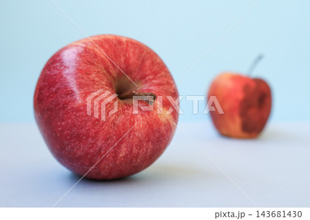 Fresh young apple in focus and old rotten apple blurred behind, light blue background, copy space. Concept of youth and aging, fresh versus spoiled, quality choice, food safety, life cycle Fresh young apple in focus and old rotten apple blurred behind, light blue background, copy space. Concept of youth and aging, fresh versus spoiled, quality choice, food safety, life cycle 143681430