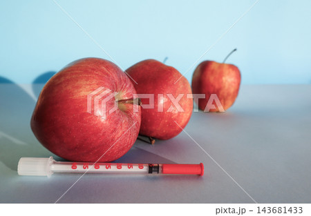 Fresh young apples beside syringe with wrinkled apple behind on light blue background, copy space. Concept of anti-aging, cosmetology injections, rejuvenation, skin care, youth and aging Fresh young apples beside syringe with wrinkled apple behind on light blue background, copy space. Concept of anti-aging, cosmetology injections, rejuvenation, skin care, youth and aging 143681433