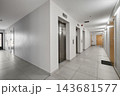 Modern apartment building corridor with steel elevator doors, white walls, and apartment entrance doors. 143681577