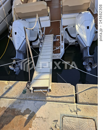 Aluminum Gangway Connecting Docked Motorboat to Concrete Pier 143682308