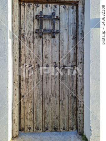 Antique Weathered Wooden Door with Iron Studs and Grate 143682309