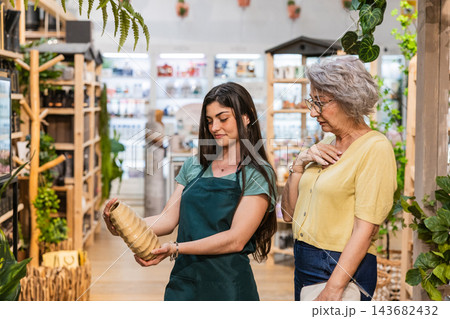 Florist worker helping customer choosing ceramic vase 143682432