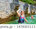 Happy family in thermal bath, relaxing under flowing water stream of shower in natural mineral hot spring Air Panas Banjar. Family day tour on vacation. Popular travel destination in Bali 143683113