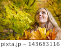 Portrait of a young woman holding colorful autumn maple leaves in a forest. Seasonal lifestyle, fall foliage, outdoor recreation and the beauty of nature during golden autumn. 143683116