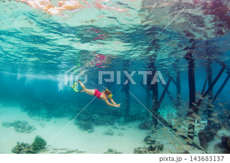 Happy family - active girl in snorkeling mask dive underwater, see tropical fishes in coral reef sea pool. Travel adventure, swimming activity and watersports on summer beach vacation with kids. Happy family - active girl in snorkeling mask dive underwater, see tropical fishes in coral reef sea pool. Travel adventure, swimming activity and watersports on summer beach vacation with kids. 143683137