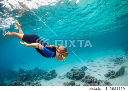 Happy family - active girl in snorkeling mask dive underwater, see tropical fishes in coral reef sea pool. Travel adventure, swimming activity and watersports on summer beach vacation with kids. 143683139
