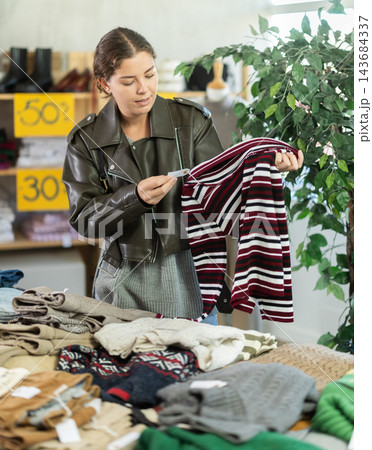 European woman chooses jersey sweater in store European woman chooses jersey sweater in store 143684337