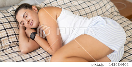 Adult woman sleeping on bed in bedroom Adult woman sleeping on bed in bedroom 143684402