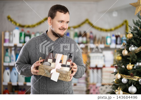 Man selecting gift set with toiletries in Christmas decorated store Man selecting gift set with toiletries in Christmas decorated store 143684496