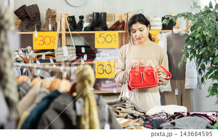 Latina chooses a stylish handbag in a clothing store Latina chooses a stylish handbag in a clothing store 143684595