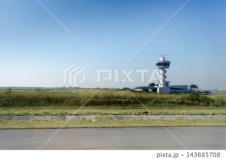 Airport Control Tower with Wide Blue Sky and Open Airfield Landscape Airport Control Tower with Wide Blue Sky and Open Airfield Landscape 143685708