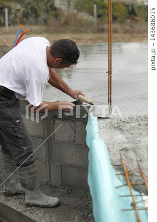 Construction Worker Smoothing Wet Concrete Foundation Construction Worker Smoothing Wet Concrete Foundation 143686015