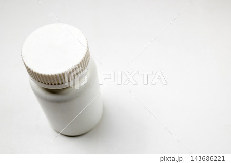 A close-up high-angle view of a white plastic medicine bottle with a ribbed cap on a neutral white background, ideal for healthcare, pharmaceutical, and medical design concepts. 143686221