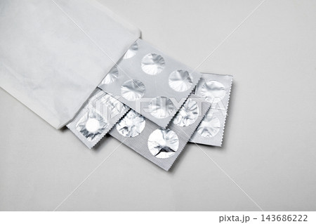 Silver blister packs of pills spilling out of a white paper pharmacy bag on a light background. Silver blister packs of pills spilling out of a white paper pharmacy bag on a light background. 143686222